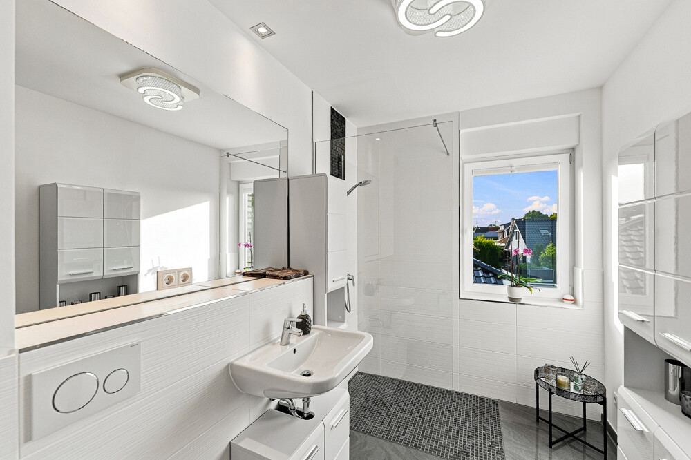 Zweites Badezimmer im Obergeschoss mit bodengleicher Dusche und Fenster.