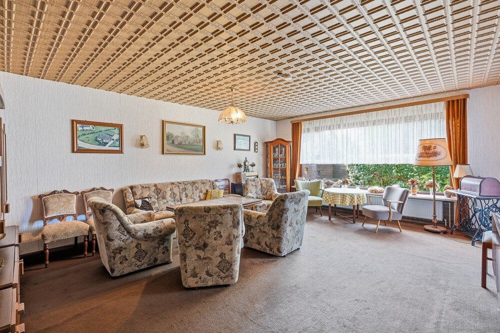 Wohnzimmer mit Sitzgruppe und Fensterfront zum Garten.